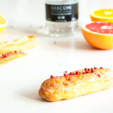 Gin and Citrus Éclairs – These éclairs are filled with a zesty, boozy pastry cream with lemon, orange and pink grapefruit and topped with a tangy fresh citrus glaze and pink peppercorns. An elegant party dessert recipe. By @deliciouscratch | deliciousfromscratch.com