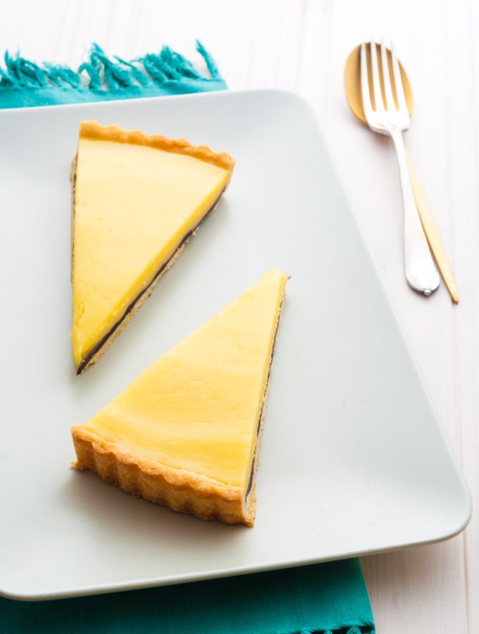 Lemon Tart with the Surprise! This French lemon tart recipe is made with homemade sweet pastry and tangy lemon curd, with a surprise layer of bitter dark chocolate to balance the sweetness. A spectacular celebration dessert for a crowd. By @deliciouscratch | deliciousfromscratch.com